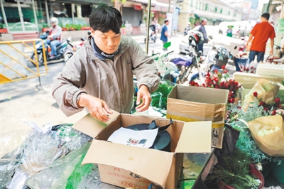 在泰国曼谷帕空鲜花市场的一家花店，快递人员将由云南鲜花制作成的花盒取走配送。新华社记者 张可任摄